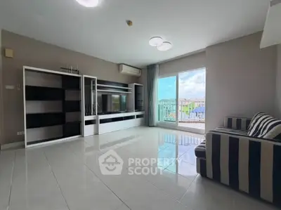Spacious living room with modern entertainment center and large window offering a bright, airy atmosphere.