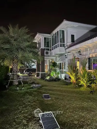 Luxurious modern villa with lush garden and elegant night lighting, showcasing exquisite architectural design.