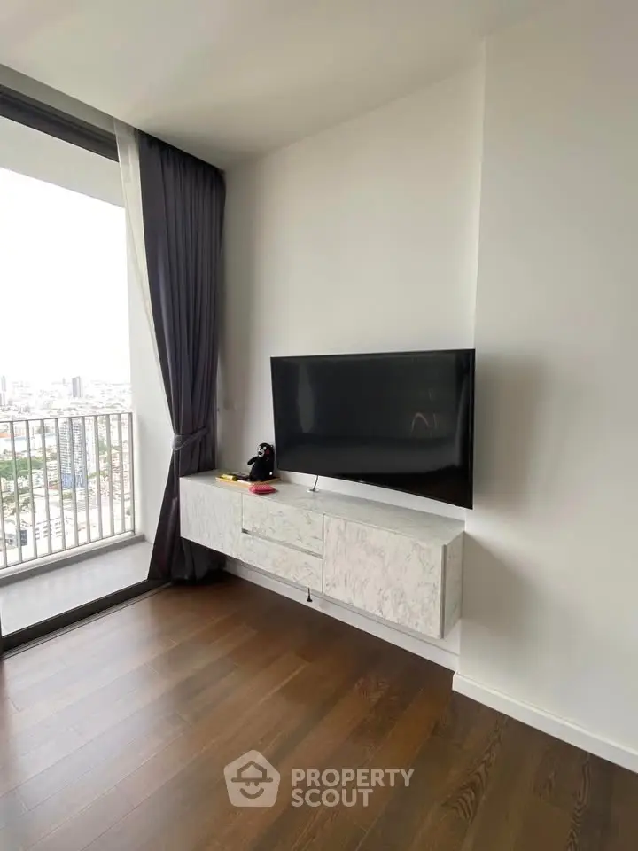 Modern living room with sleek TV setup and city view balcony.