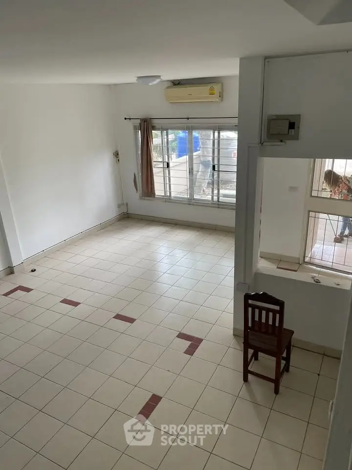 Spacious unfurnished room with tiled flooring and large window, ideal for customization.