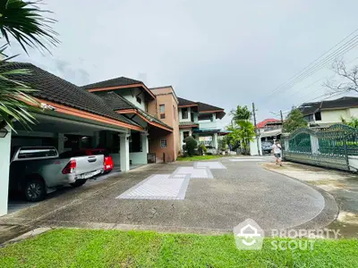 Spacious driveway leading to a modern two-story house with carport and lush greenery.