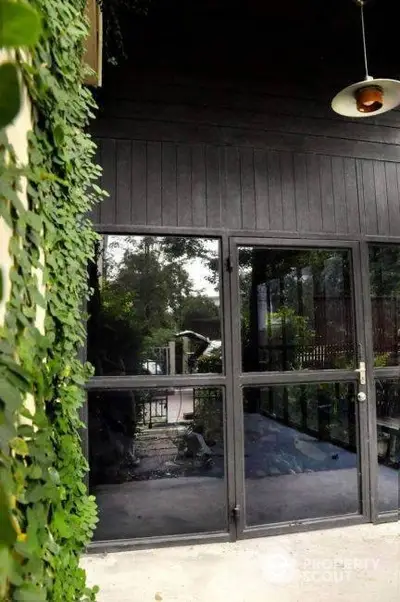 Modern building entrance with glass doors and lush greenery