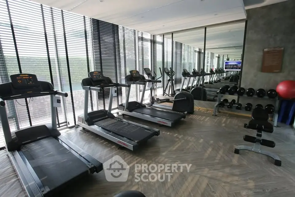 Modern gym with treadmills and weights in a luxury apartment complex.