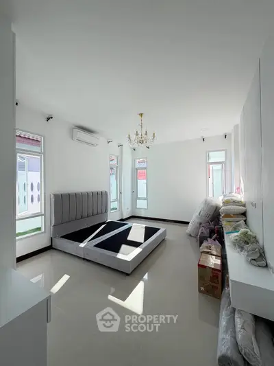 Spacious bedroom with modern bed frame and elegant chandelier in a bright, airy setting.