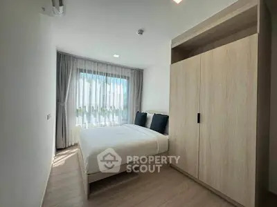 Modern bedroom with large window and stylish wardrobe in a bright apartment.