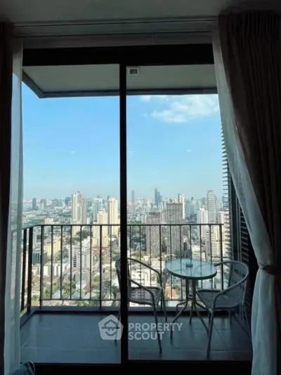 Stunning city view from a high-rise balcony with cozy seating area.