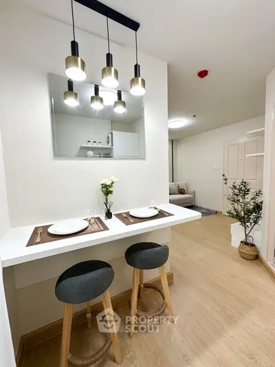 Modern dining area with stylish pendant lights and cozy seating in a contemporary apartment.