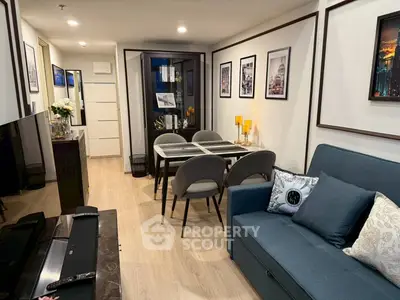 Modern living room with stylish decor and dining area, featuring elegant furniture and framed wall art.
