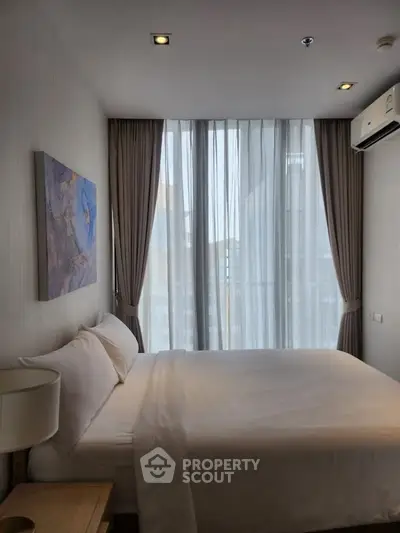 Modern bedroom with large window and stylish decor in urban apartment.