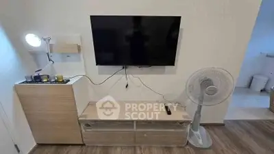 Modern living room with mounted TV, sleek wooden furniture, and a standing fan for comfort.