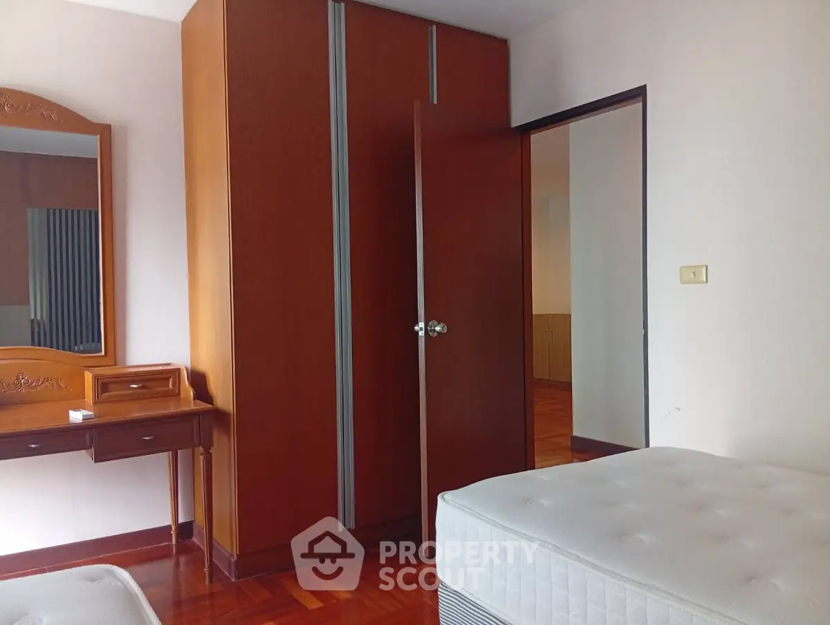 Spacious bedroom with wooden wardrobe and elegant vanity in a cozy apartment.