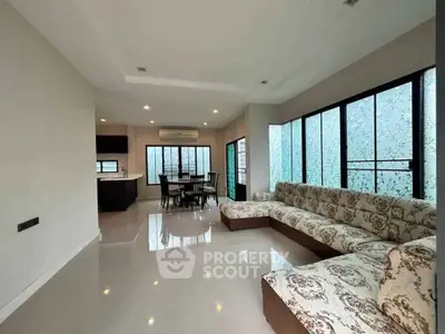 Spacious living room with elegant sectional sofa and dining area, featuring large windows for natural light.