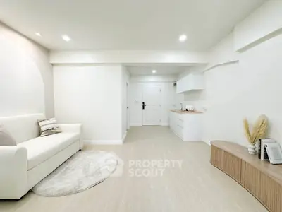 Modern minimalist living room with white sofa and sleek kitchen area