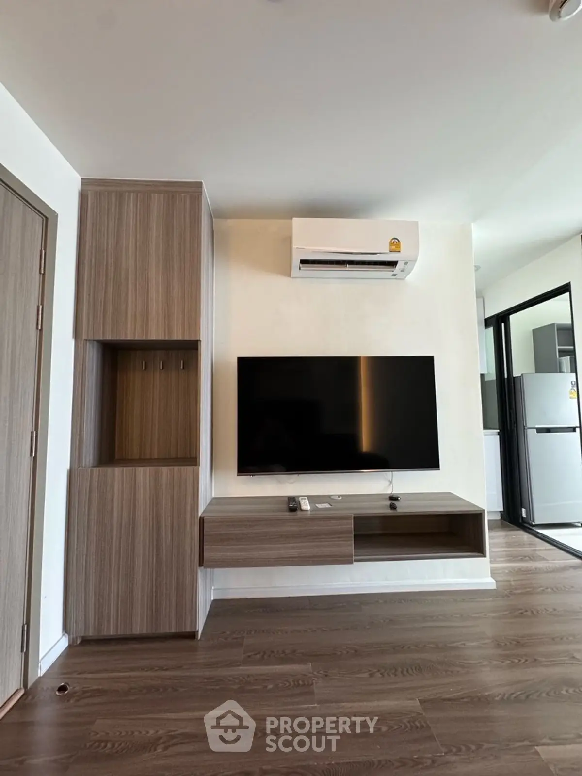Modern living room with wall-mounted TV and air conditioner, featuring sleek wooden cabinetry.