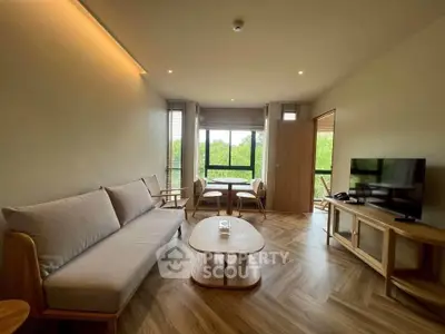 Modern living room with stylish furniture and large window offering lush green views.
