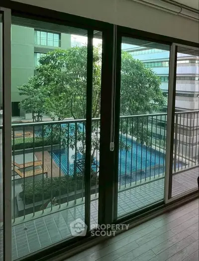 Spacious balcony view overlooking a serene pool and lush greenery in a modern apartment complex.