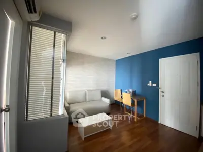 Modern living room with blue accent wall, sleek furniture, and wooden flooring