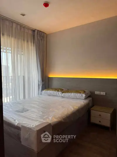 Cozy bedroom with modern lighting and large window, perfect for relaxation and comfort.