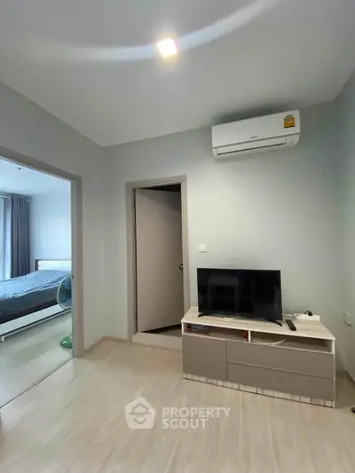 Modern living room with TV and air conditioning, adjacent to a cozy bedroom.