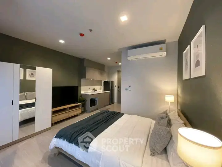Modern bedroom with stylish decor and compact kitchen area in open layout apartment.
