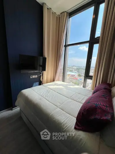 Luxurious bedroom with floor-to-ceiling windows offering stunning city views, elegant decor, and modern amenities.