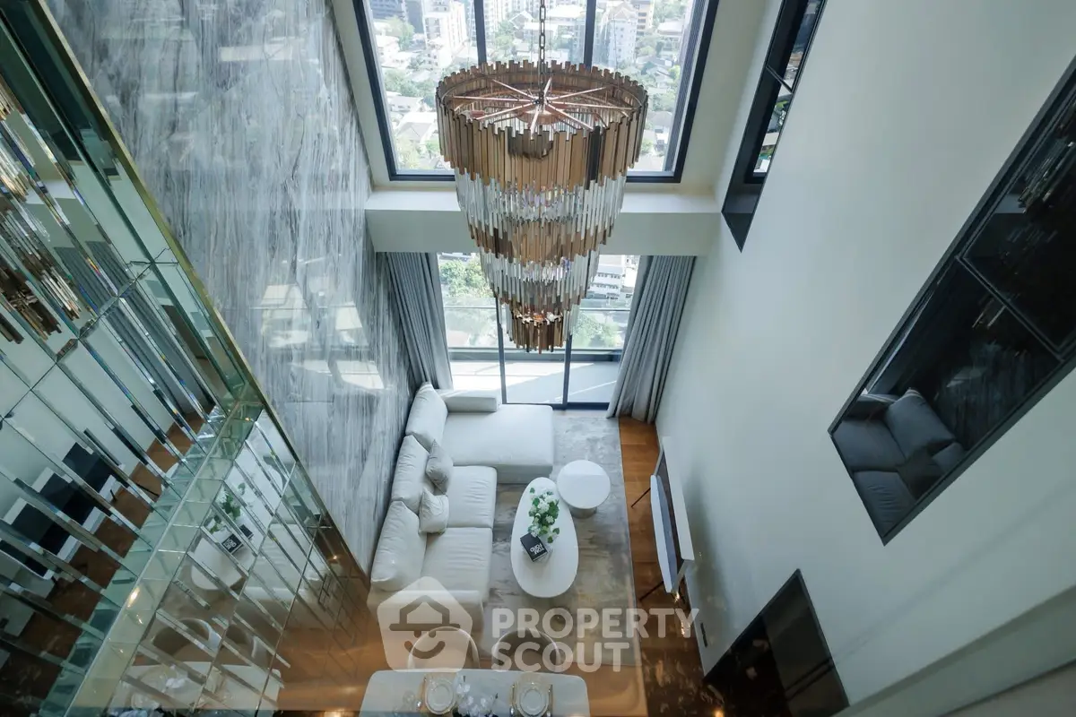 Luxurious high-ceiling living room with stunning city view and elegant chandelier.