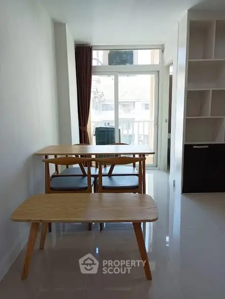 Bright dining area with modern wooden table and chairs, large window, and built-in shelving.