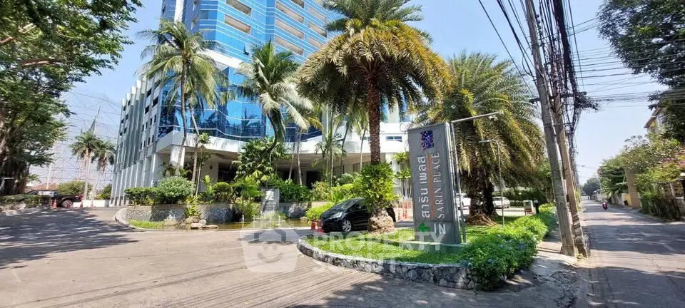 Modern high-rise building with lush landscaping and clear blue sky, showcasing urban living at its finest.
