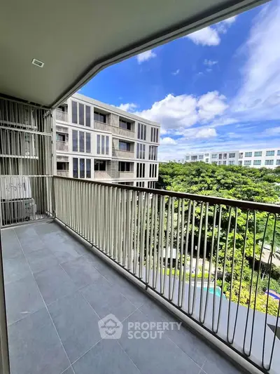 Spacious balcony with stunning view of modern buildings and lush greenery, perfect for relaxation.