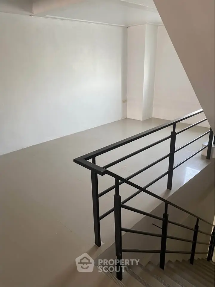 Spacious stairway landing in modern building with sleek railing design.
