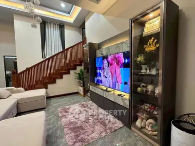 Spacious living room with modern decor and entertainment center, featuring a cozy seating area and elegant staircase.