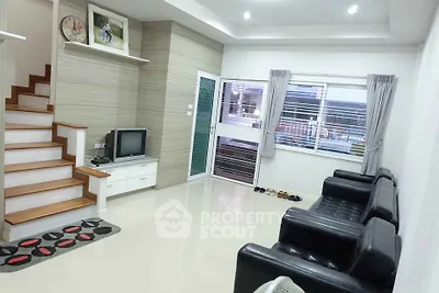 Modern living room with sleek black sofas and stylish staircase