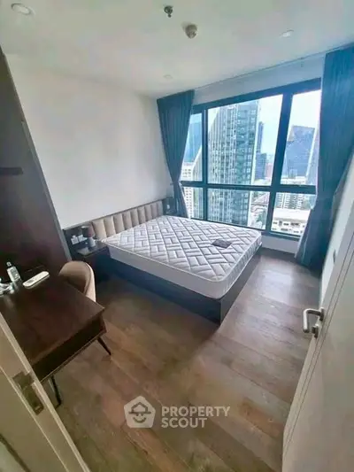 Modern bedroom with stunning city view, featuring a cozy bed and elegant wooden flooring.