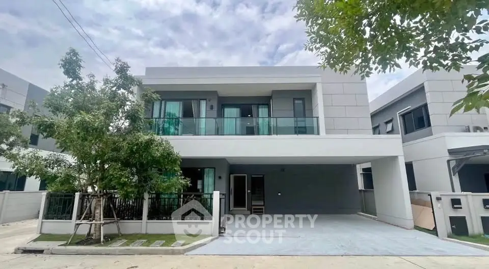 Modern two-story house with spacious driveway and balcony in a serene neighborhood.