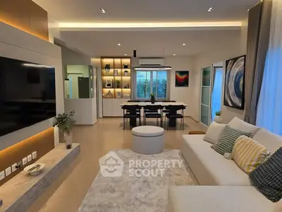 Modern living room with stylish decor and open layout, featuring a large TV and elegant dining area.