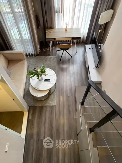 Modern loft-style living room with high ceilings, large windows, and stylish furniture.