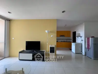 Spacious living room with modern kitchen in open layout, featuring sleek appliances and natural light.