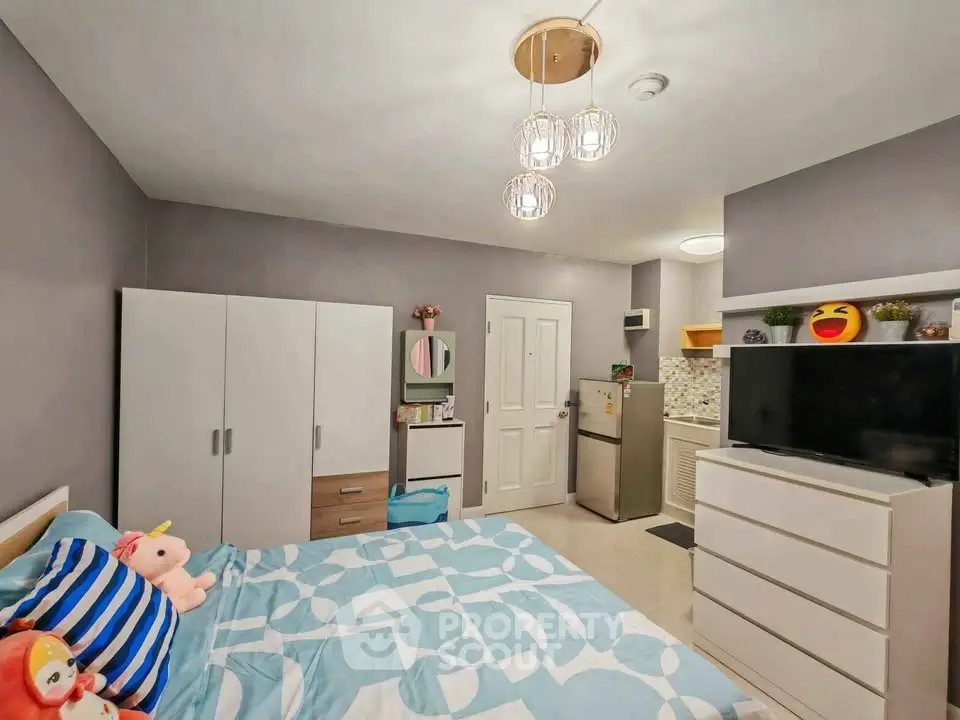 Cozy bedroom with modern decor and compact kitchen area, perfect for urban living.