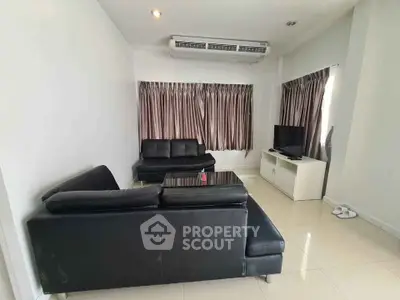 Modern living room with sleek black leather sofas and large windows, perfect for relaxation and entertainment.