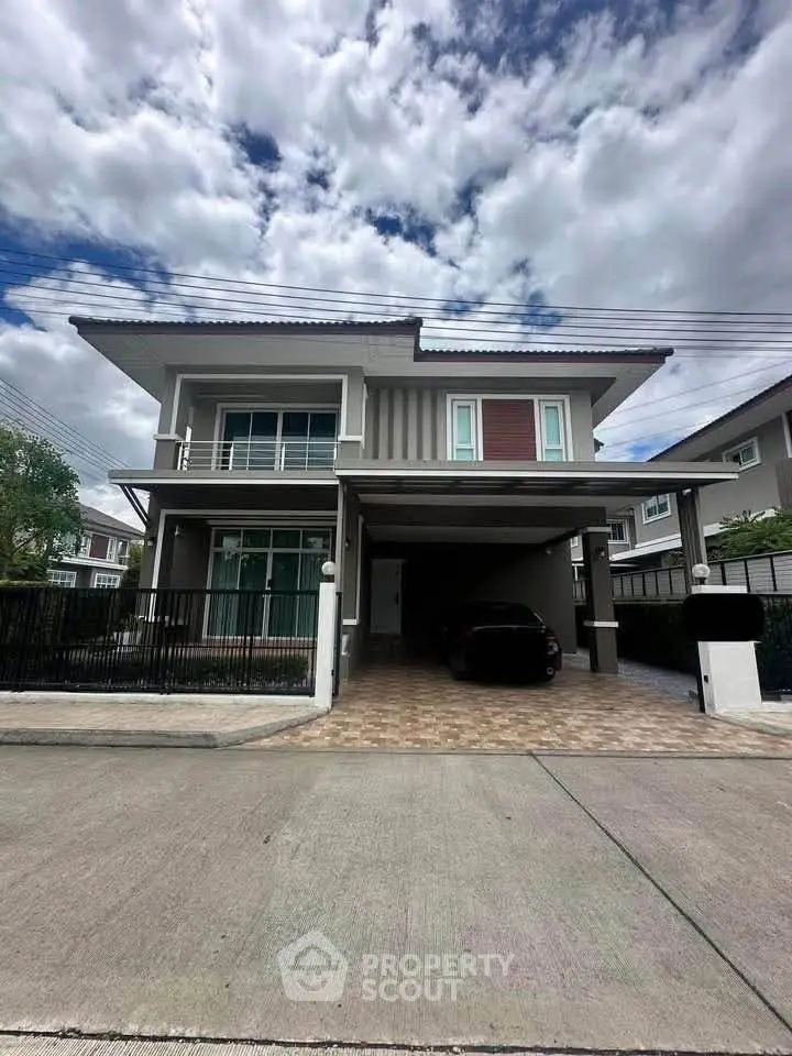 Modern two-story house with carport and stylish facade under a cloudy sky.