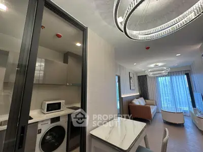 Modern apartment interior with stylish lighting, open living area, and compact kitchen featuring appliances.