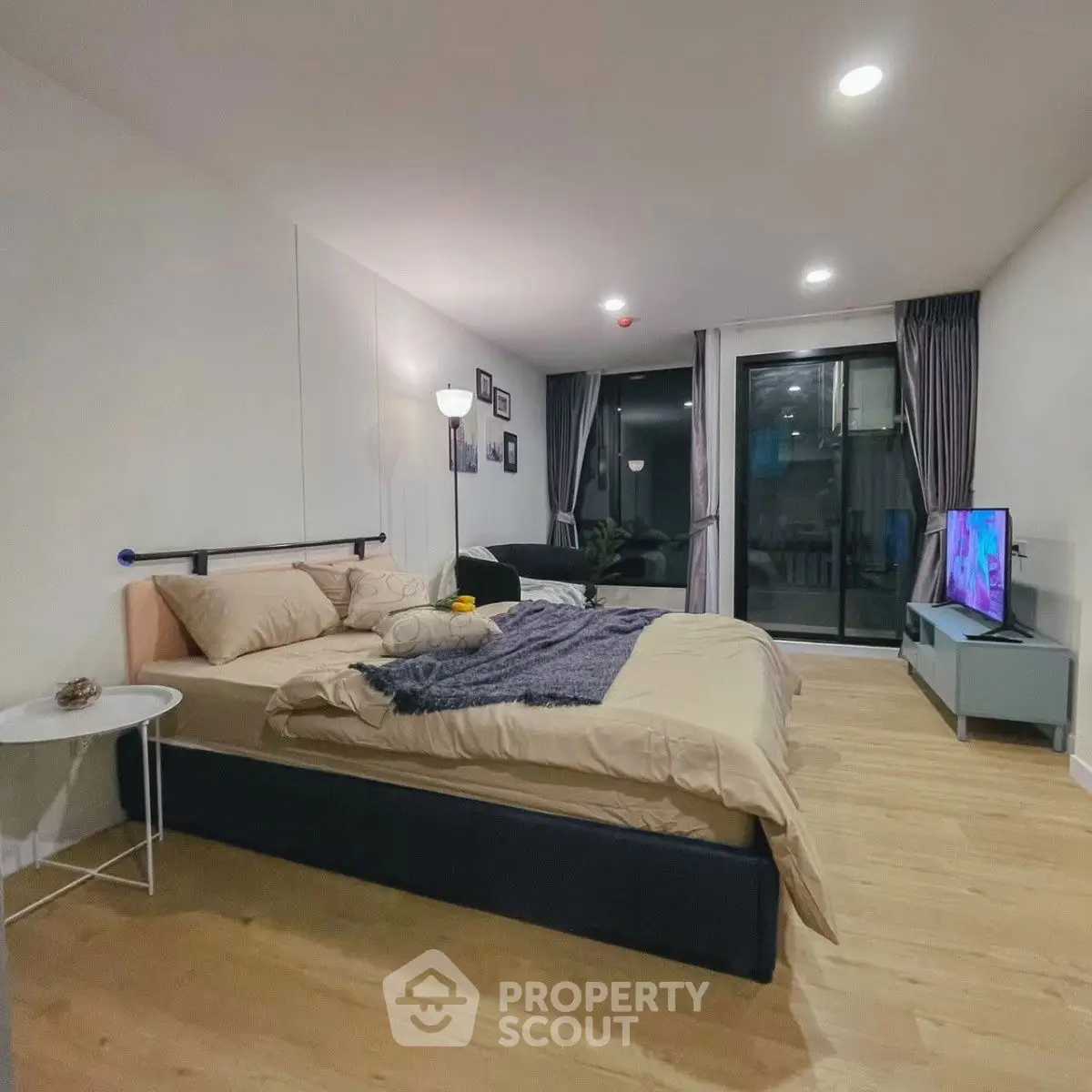 Spacious modern bedroom with cozy decor and large window view.