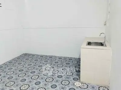 Minimalist kitchen area with patterned tile flooring and compact sink unit.