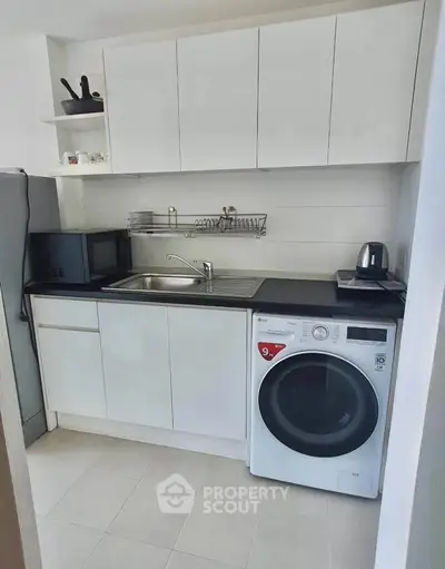 Modern compact kitchen with sleek white cabinets and built-in appliances, perfect for urban living.