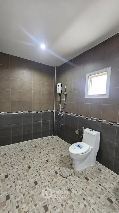 Modern bathroom with tiled walls and floor, featuring a toilet and shower area.