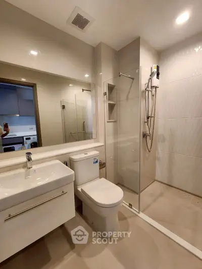 Modern bathroom with sleek fixtures and glass shower enclosure in a contemporary apartment.
