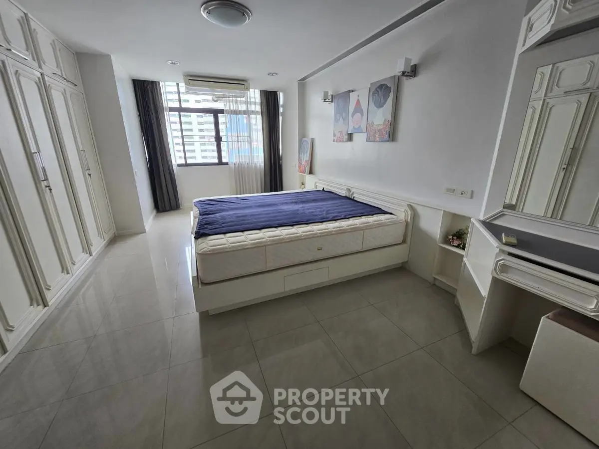 Spacious bedroom with large windows and built-in wardrobes in modern apartment
