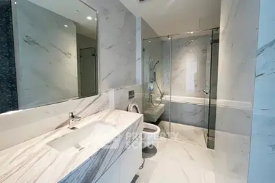 Luxurious modern bathroom with marble finishes and glass shower enclosure.