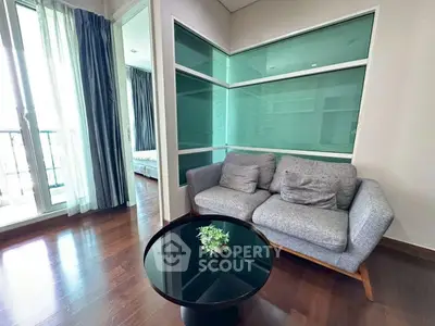 Modern living room with stylish sofa and glass coffee table, adjacent to a bright bedroom with balcony access.