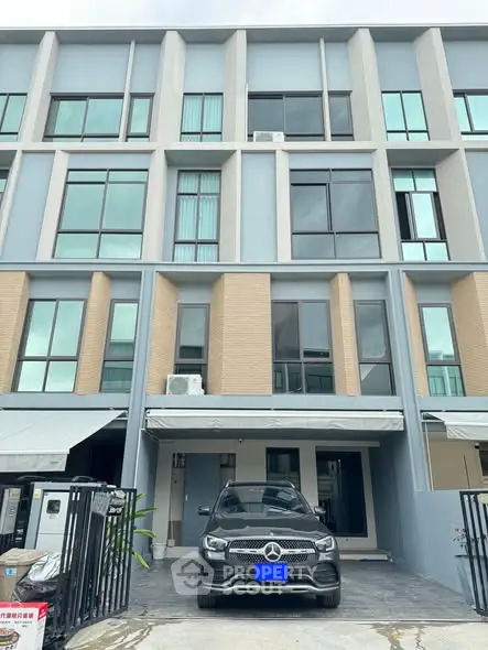 Modern townhouse with sleek facade and luxury car parked in driveway.